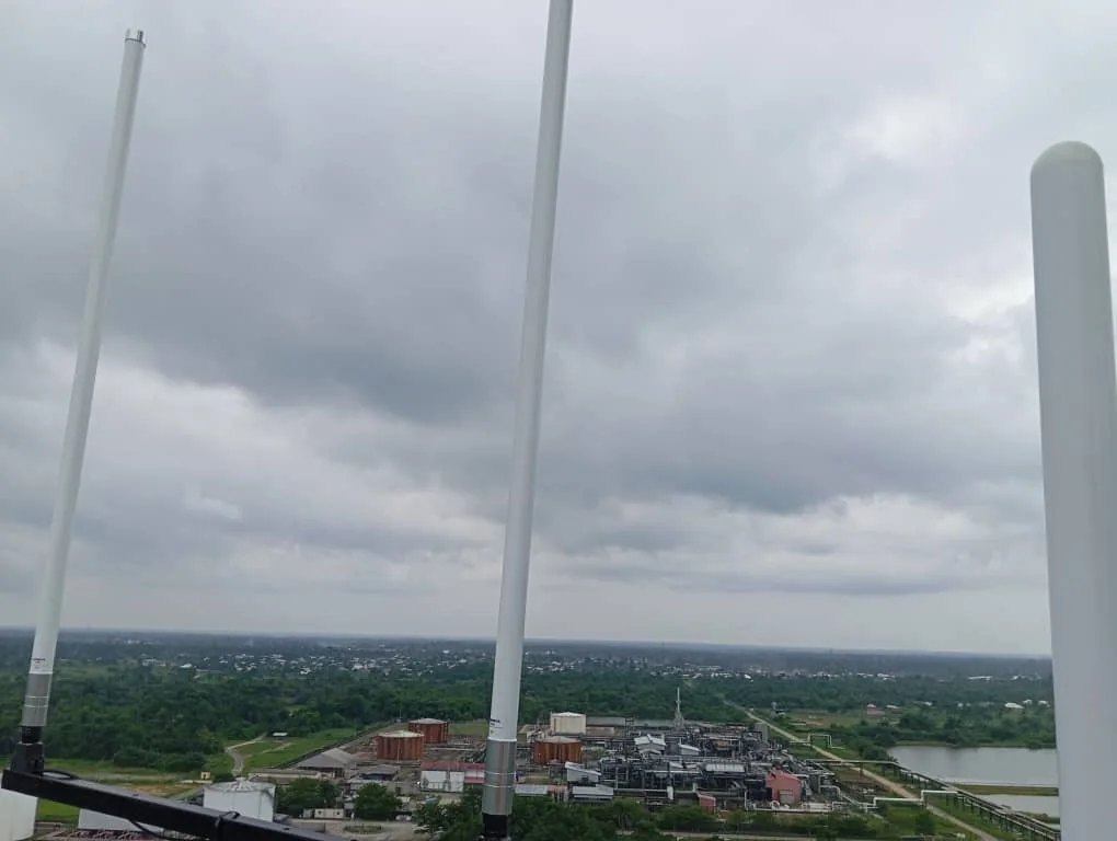Vertical radio antenna array overlooking an industrial facility